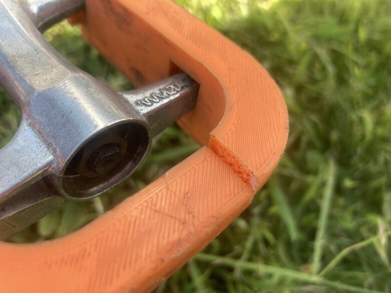 Bike pedal made of orange plastic, broken. Close up